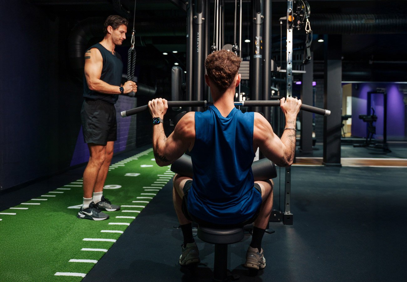 Zwei Personen trainieren an Kraftgeräten im FITOMAT-Studio.