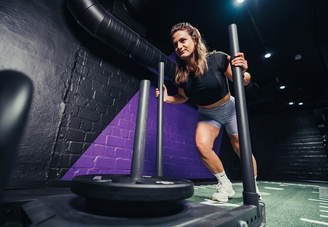 Person schiebt einen Trainingsschlitten im Functional-Bereich des FITOMAT-Studios.